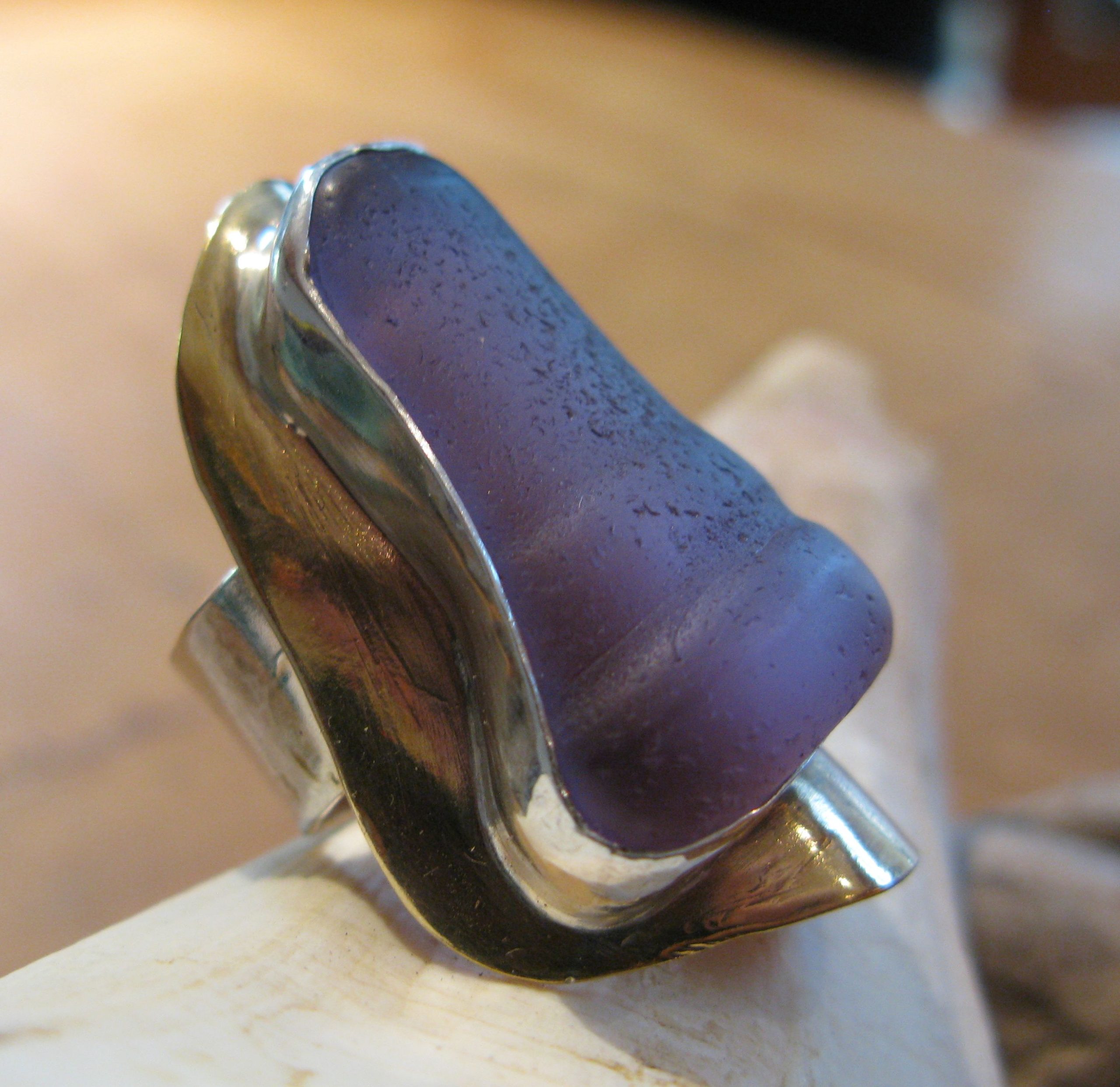 Purple glass from a bottle top with silver bezel and brass base formed to fit the inside curvature of the glass